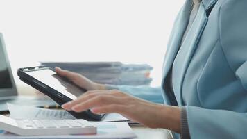 Asian Businesswoman Using laptop computer and working at office with calculator document on desk, doing planning analyzing the financial report, business plan investment, finance analysis concept. video