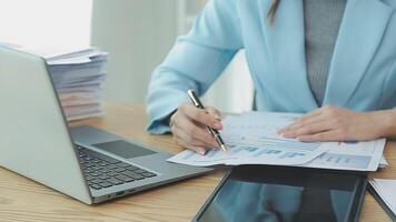 Asian Businesswoman Using laptop computer and working at office with calculator document on desk, doing planning analyzing the financial report, business plan investment, finance analysis concept. video