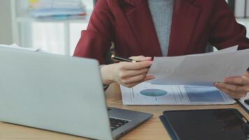 Asian Businesswoman Using laptop computer and working at office with calculator document on desk, doing planning analyzing the financial report, business plan investment, finance analysis concept. video