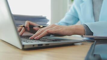 Asian Businesswoman Using laptop computer and working at office with calculator document on desk, doing planning analyzing the financial report, business plan investment, finance analysis concept. video