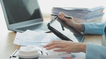 Asian Businesswoman Using laptop computer and working at office with calculator document on desk, doing planning analyzing the financial report, business plan investment, finance analysis concept. video