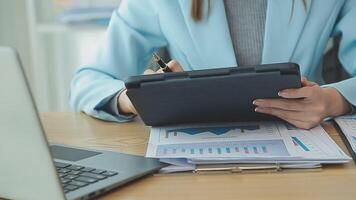 Asian Businesswoman Using laptop computer and working at office with calculator document on desk, doing planning analyzing the financial report, business plan investment, finance analysis concept. video
