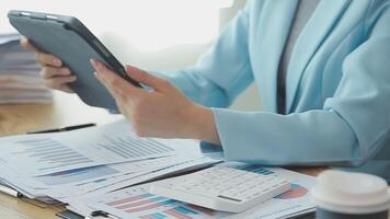 Asian Businesswoman Using laptop computer and working at office with calculator document on desk, doing planning analyzing the financial report, business plan investment, finance analysis concept. video