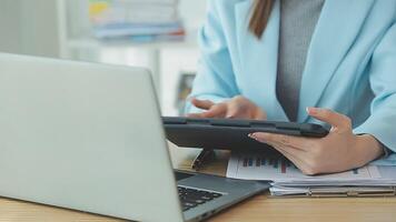 Asian Businesswoman Using laptop computer and working at office with calculator document on desk, doing planning analyzing the financial report, business plan investment, finance analysis concept. video