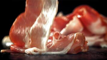 Fresh bacon falling on black background. Filmed on a high-speed camera at 1000 fps. High quality FullHD footage video