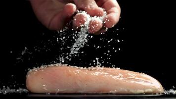 A man sprinkles salt on chicken meat. Filmed on a high-speed camera at 1000 fps. High quality FullHD footage video