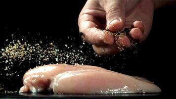 A man sprinkles spices on chicken fillet. Filmed on a high-speed camera at 1000 fps. High quality FullHD footage video