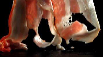 Fresh bacon falling on black background. Filmed on a high-speed camera at 1000 fps. High quality FullHD footage video