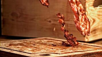 Roasted slices of bacon fall on a wooden table. Filmed on a high-speed camera at 1000 fps. High quality FullHD footage video