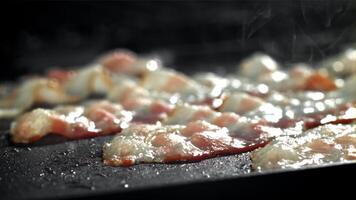 el tocino es frito en un pan con un chapoteo de aceite. filmado en un alta velocidad cámara a 1000 fps. alto calidad full HD imágenes video