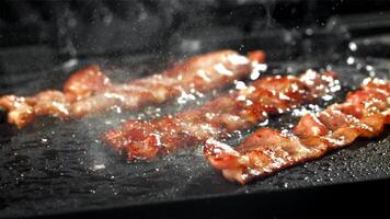 il Bacon è fritte nel un' padella con un' spruzzo di olio. girato su un' alta velocità telecamera a 1000 fps. alto qualità FullHD metraggio video