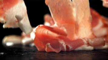 Fresh bacon falling on black background. Filmed on a high-speed camera at 1000 fps. High quality FullHD footage video