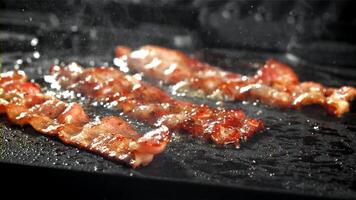 a bacon é frito dentro uma panela com uma respingo do óleo. filmado em uma alta velocidade Câmera às 1000 fps. Alto qualidade fullhd cenas video