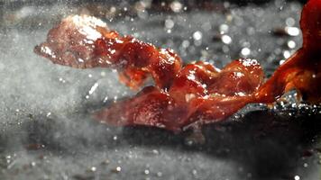 bacon é frito dentro uma frigideira. filmado em uma alta velocidade Câmera às 1000 fps. Alto qualidade fullhd cenas video