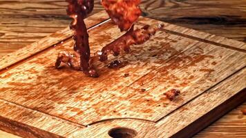 Roasted slices of bacon fall on a wooden table. Filmed on a high-speed camera at 1000 fps. High quality FullHD footage video