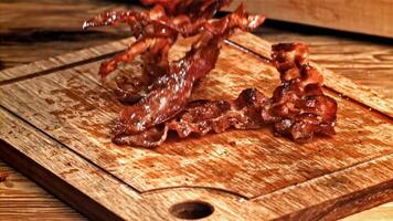 Roasted slices of bacon fall on a wooden table. Filmed on a high-speed camera at 1000 fps. High quality FullHD footage video