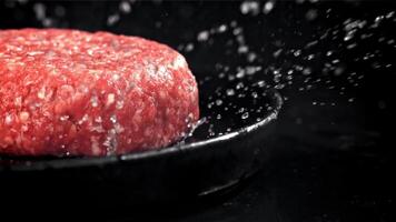une Frais Viande Burger chutes sur une noir tableau. filmé sur une haute vitesse caméra à 1000 ips. haute qualité Full HD métrage video
