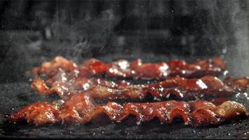 el tocino es frito en un pan con un chapoteo de aceite. filmado en un alta velocidad cámara a 1000 fps. alto calidad full HD imágenes video