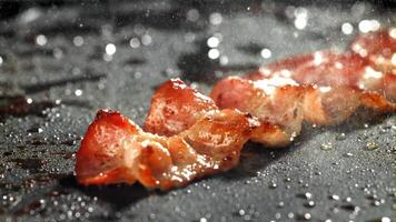 a bacon é frito dentro uma panela com uma respingo do óleo. filmado em uma alta velocidade Câmera às 1000 fps. Alto qualidade fullhd cenas video