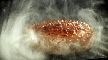 un' Manzo hamburger cascate in un' caldo padella con un' spruzzo di olio. girato su un' alta velocità telecamera a 1000 fps. alto qualità FullHD metraggio video