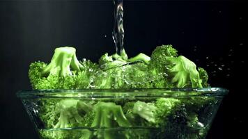 en ström av vatten häller in i en tallrik av broccoli. filmad på en hög hastighet kamera på 1000 fps. hög kvalitet full HD antal fot video