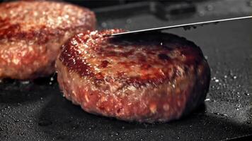 een rundvlees hamburger valt in een heet pan met een plons van olie. gefilmd Aan een hoge snelheid camera Bij 1000 fps. hoog kwaliteit full HD beeldmateriaal video