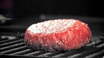 uma carne hamburguer cai para dentro uma quente panela com uma respingo do óleo. filmado em uma alta velocidade Câmera às 1000 fps. Alto qualidade fullhd cenas video