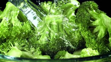 A stream of water pours into a plate of broccoli. Filmed on a high-speed camera at 1000 fps. High quality FullHD footage video