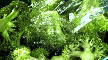 A stream of water pours into a plate of broccoli. Filmed on a high-speed camera at 1000 fps. High quality FullHD footage video