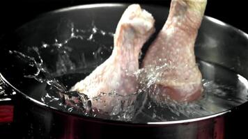 crudo pollo gambe autunno in un' pentola di acqua. girato su un' alta velocità telecamera a 1000 fps. alto qualità FullHD metraggio video