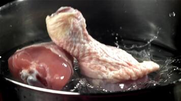 rå kyckling ben falla in i en pott av vatten. filmad på en hög hastighet kamera på 1000 fps. hög kvalitet full HD antal fot video