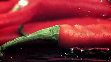 Chili peppers fall on a wet black table. Filmed on a high-speed camera at 1000 fps. High quality FullHD footage video