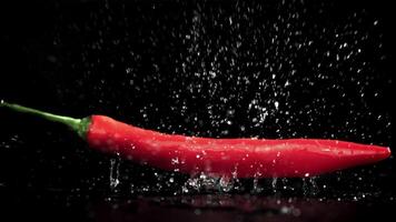 Chili paprika's vallen Aan een nat zwart tafel. gefilmd Aan een hoge snelheid camera Bij 1000 fps. hoog kwaliteit full HD beeldmateriaal video