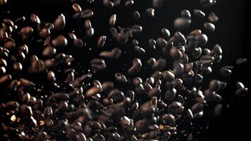 Coffee beans fly in different directions. On a black background. Filmed on a high-speed camera at 1000 fps. High quality FullHD footage video