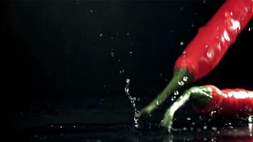 Chili peppers fall on a wet black table. Filmed on a high-speed camera at 1000 fps. High quality FullHD footage video