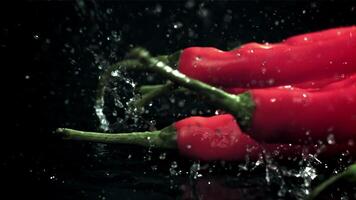 Chili peppers fall on a wet black table. Filmed on a high-speed camera at 1000 fps. High quality FullHD footage video