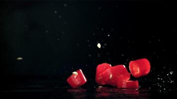 Sliced chunks of chili pepper falling on a black background. Filmed on a high-speed camera at 1000 fps. High quality FullHD footage video