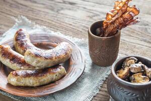 Grilled sausages with fried bacon rashers and mushrooms photo