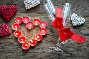 Burning candles in the shape of heart with two flutes photo