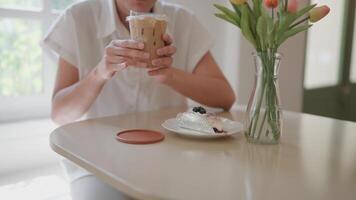 un mujer bebidas su favorito latté mientras Relajado en un café tienda. video