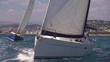 zwei Segeln Boote Schnitt durch das Wasser auf das Meer im Super schleppend Bewegung. aus das Küste von Cannes. video