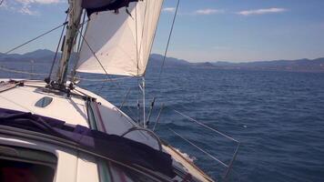 en tablero un pequeño navegación barco - estabilizado imágenes desde cardán mirando fuera a amplio Oceano y un isla en el distancia video