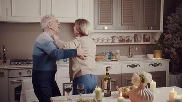 une mignonne personnes âgées couple les boissons du vin et danses dans le soir à Accueil dans le cuisine. anniversaire fête. le secret de l'amour. l'amour pour vie. video