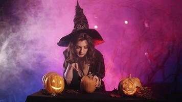 beautiful witch laughs and cuts a pumpkin for halloween video