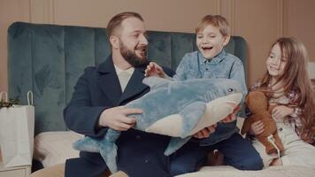 Caring father giving as a gift of a plush shark and playing peek-a-boo with his little baby. video