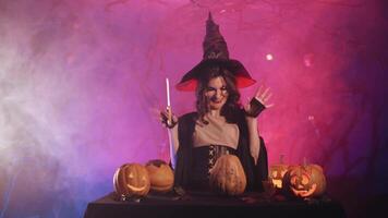 beautiful witch laughs and cuts a pumpkin for halloween. video
