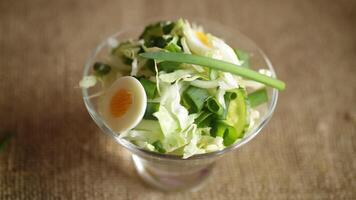 Frühling Salat mit früh Kohl, Gurken, Eier und Grün Zwiebeln auf ein hölzern Tisch. video