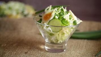 primavera insalata con presto cavolo, cetrioli, uova e verde cipolle su un' di legno tavolo. video