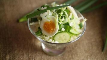 primavera insalata con presto cavolo, cetrioli, uova e verde cipolle su un' di legno tavolo. video