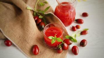 hausgemacht frisch gedrückt Tomate Saft mit Fruchtfleisch im ein Glas Karaffe, auf ein hölzern Tisch. video